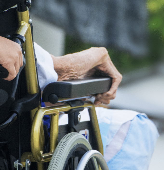 Elderly woman in wheelchair being pushed by carer; use of product for assistid living - mobility/ assistive device. 